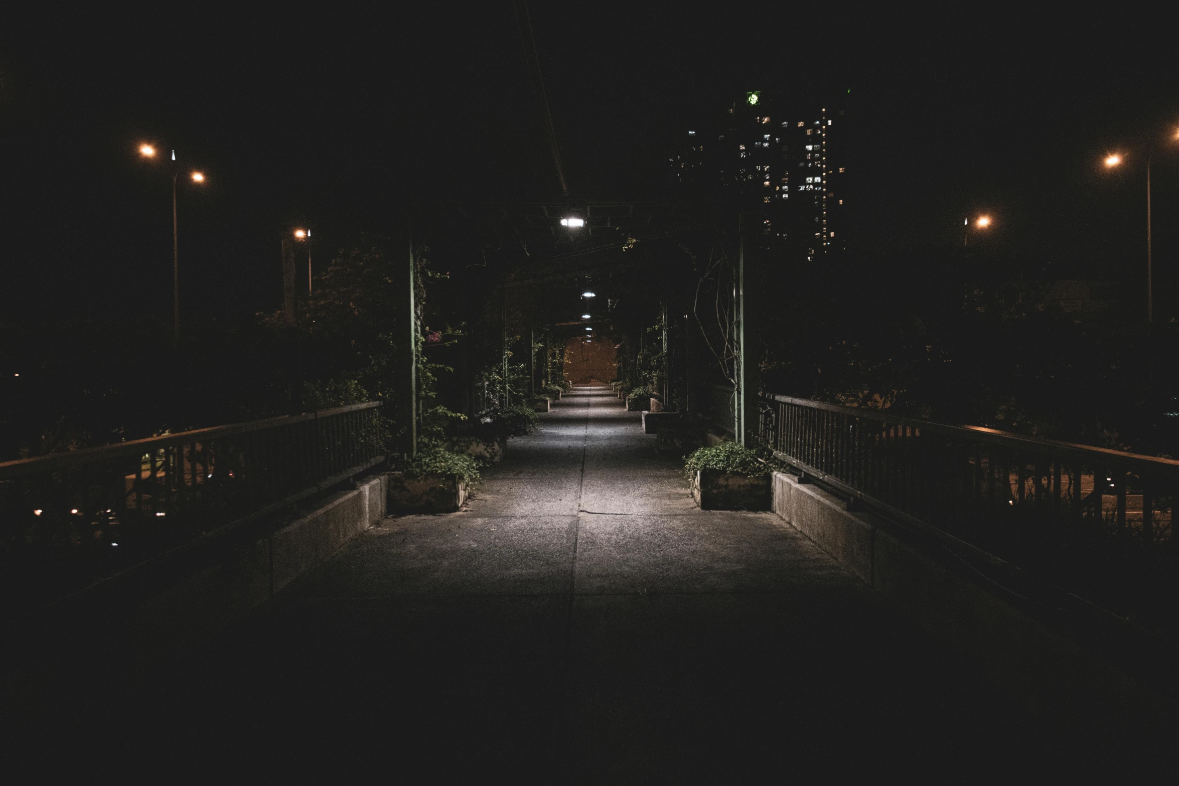 a walkway at night in the city with lights lit