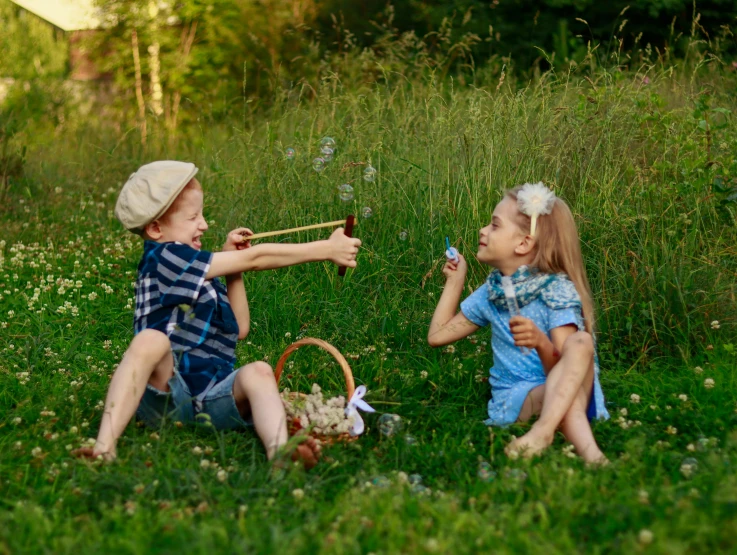 two children sitting on the grass blowing bubbles