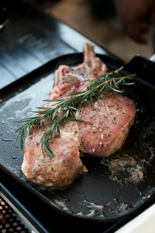 steak with herbs on the bottom of it, resting on a griddle