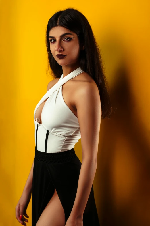 an attractive woman posing in front of a yellow wall