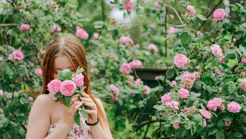 a girl in a garden holding onto roses