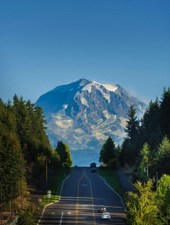 the mountains are high above the cars on the road