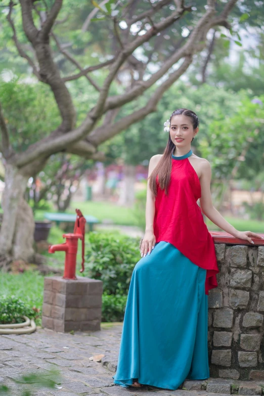 the girl in red and blue dress is leaning against a stone wall