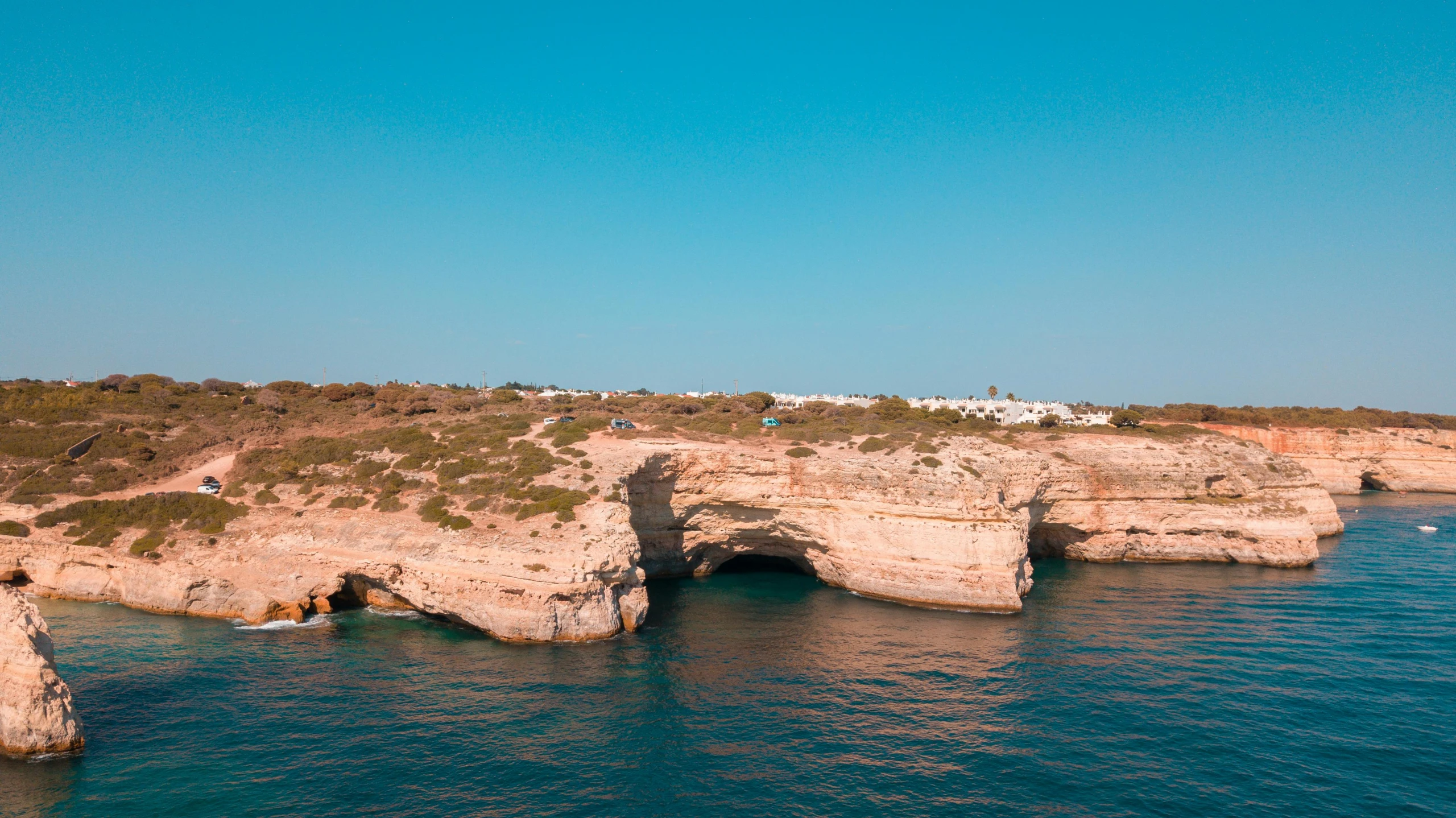 two large rocks sticking out of the water near a shore line