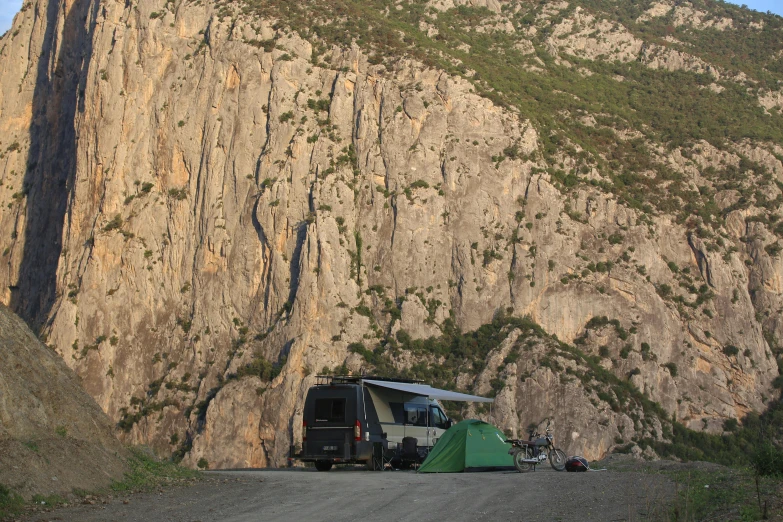 an rv parked near a large cliff on a sunny day