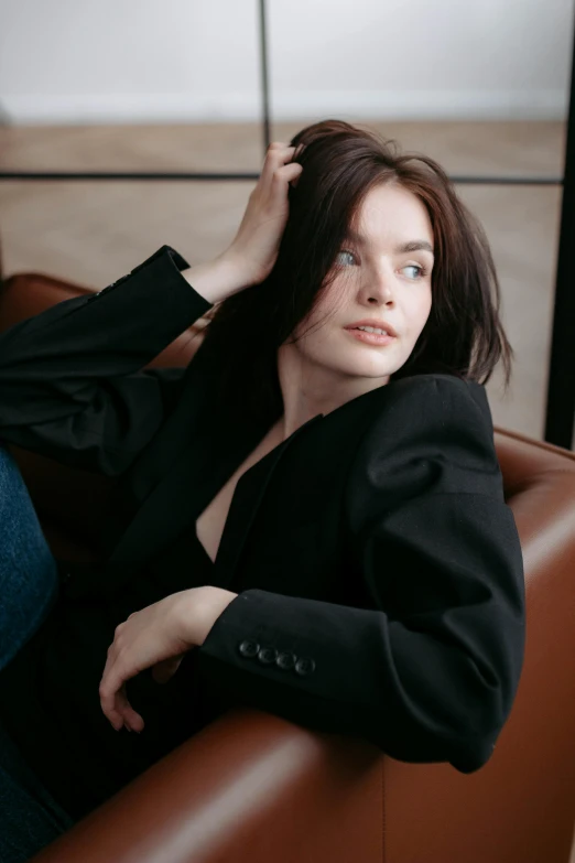 a woman sitting in a brown chair with her hand on her head