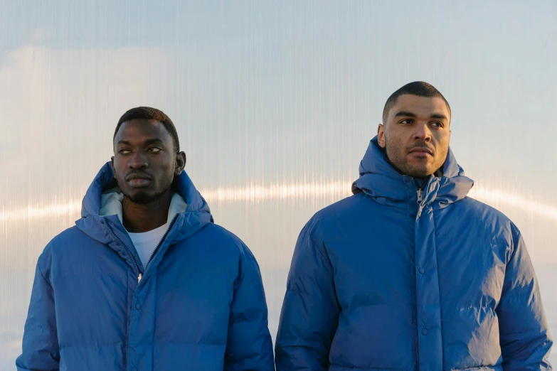 two men are standing with blue jackets over them