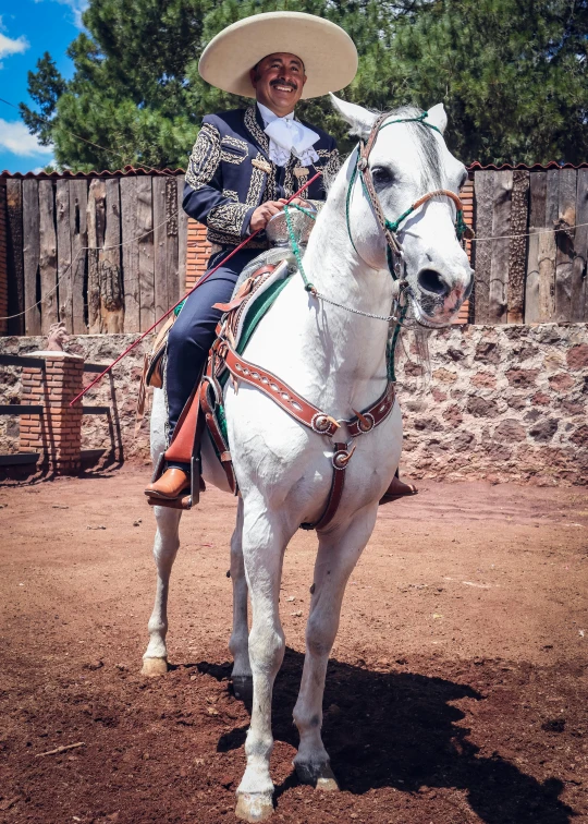 a man wearing a sombrero is riding a white horse