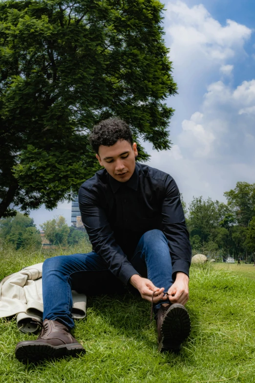a man is sitting on the grass near his boots