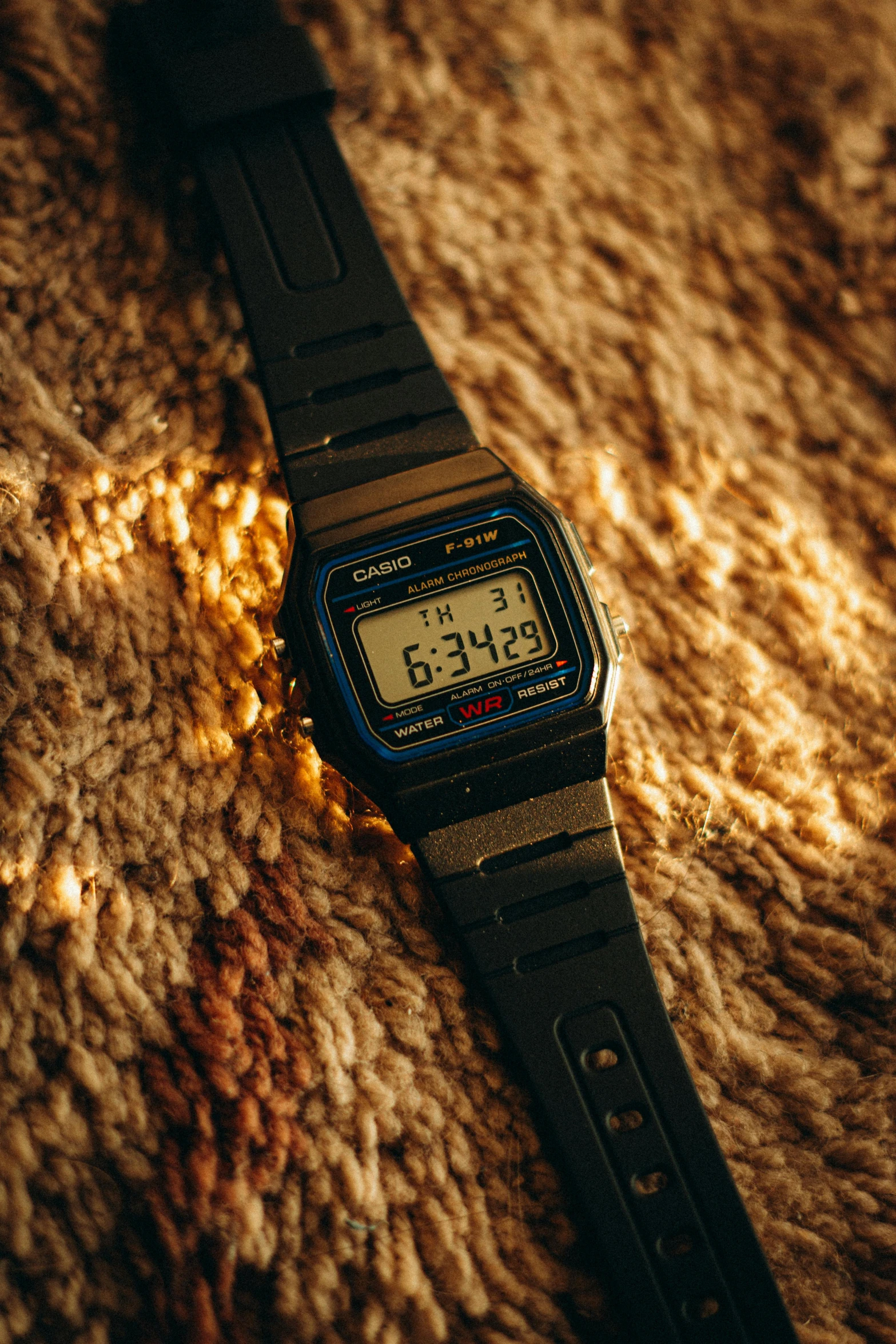 a watch sits on a carpet with sunlight coming in from behind it