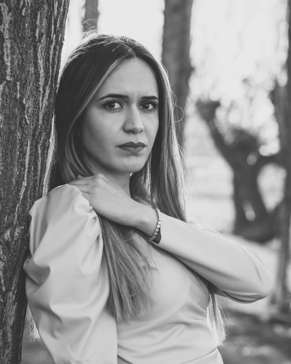 woman wearing an elegant dress, standing in front of a tree