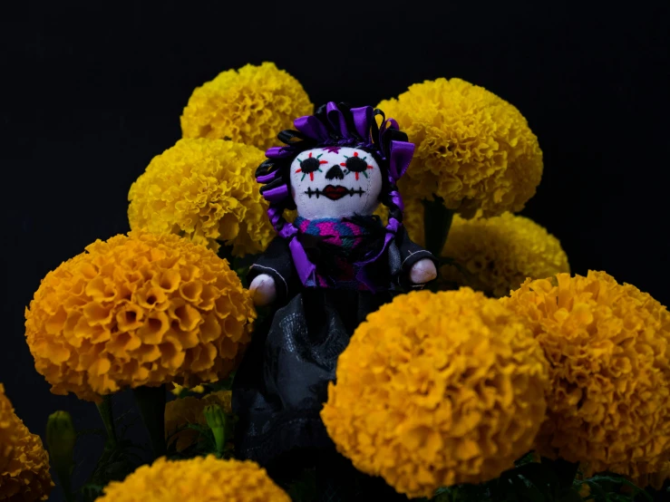 there is a doll sitting among yellow flowers