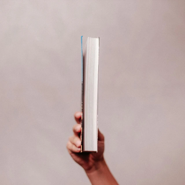 a person's hand holding a book while it covers