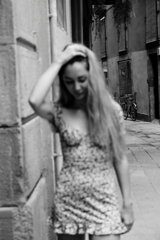 a woman with long hair leans on a wall