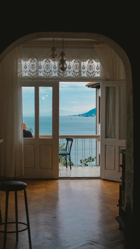 a living room has large doors and a view out to the water