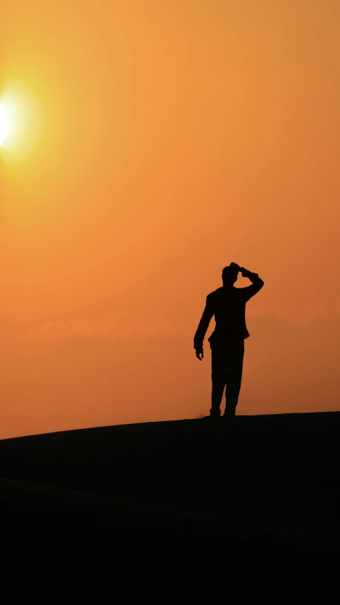 a silhouette image of a man standing at sunset