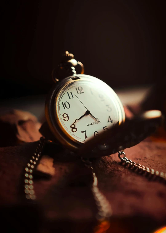 a pocket watch with gold dial and chain is placed on a table