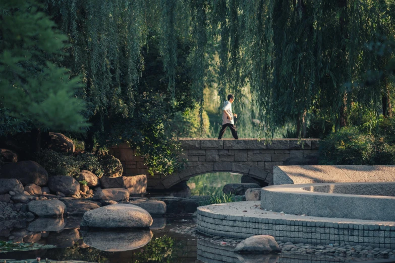 a man on a stone bridge over a river