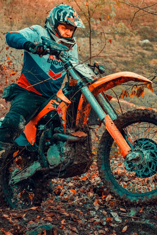 man on orange and black motorbike riding through brush