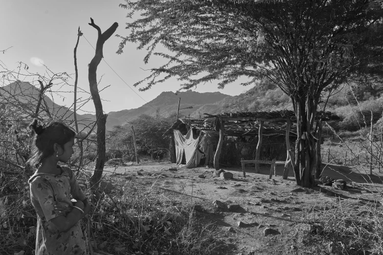 a woman in a dress standing near some trees