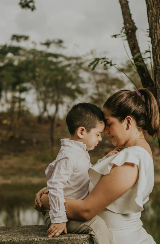 a woman holding a young child near water