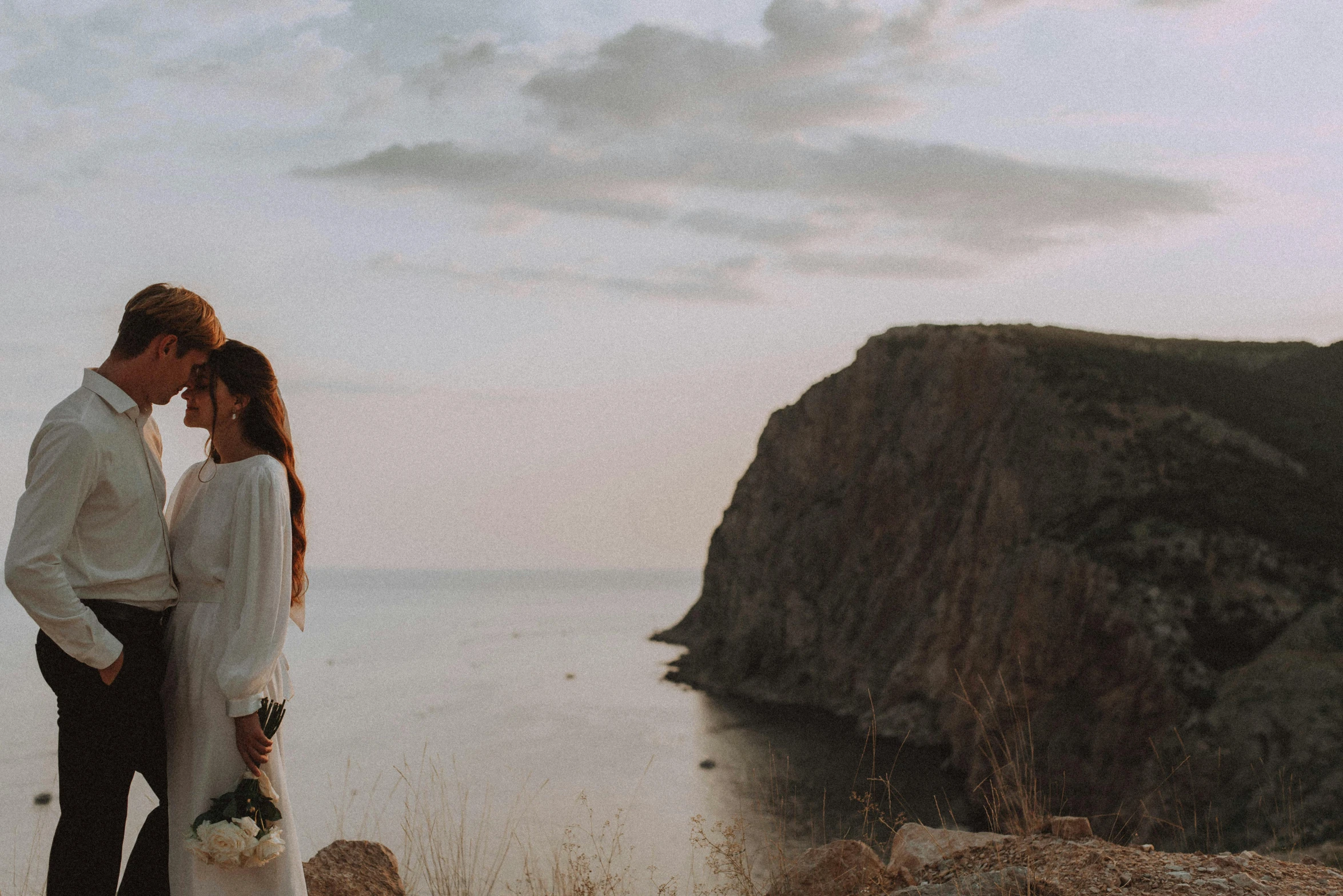 a couple poses for a po at sunset by the ocean