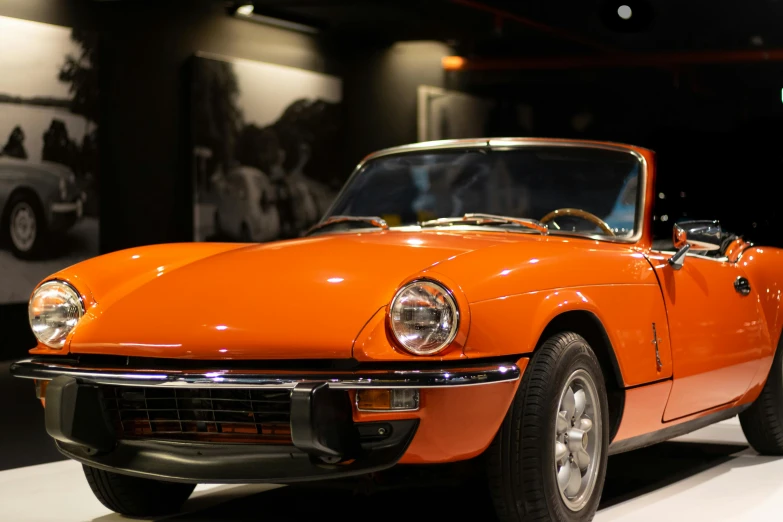 an orange sports car on display on the carpet