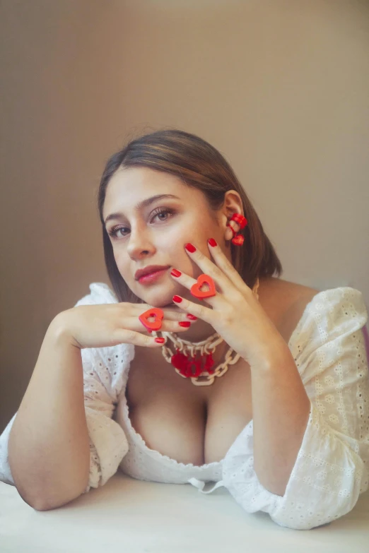 a woman with red fingernails sitting in front of a white table