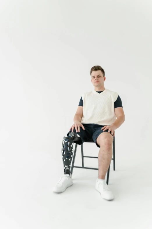 a young man sitting down on a chair holding a camera