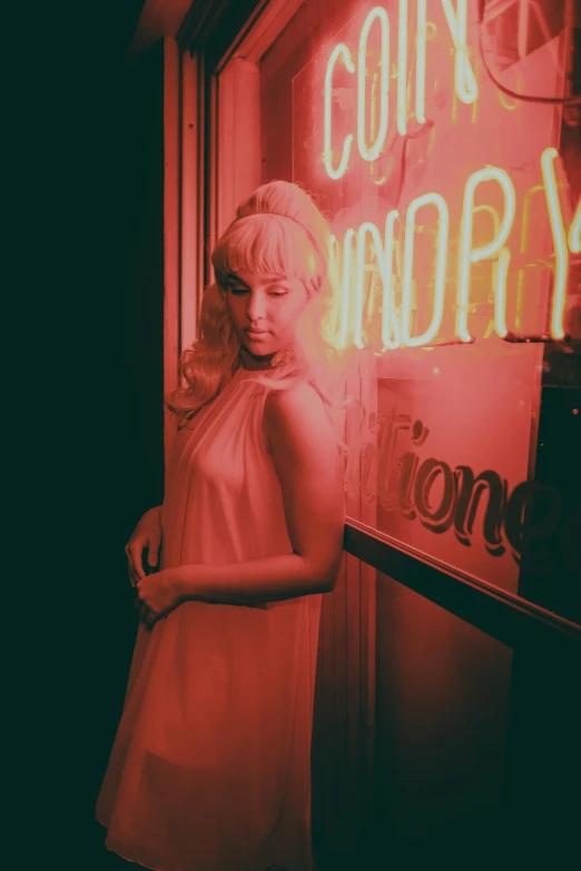 a woman is standing next to a neon sign