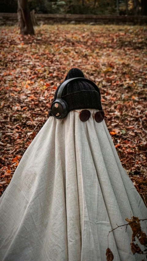 a black bonnet covered in white fabric lying in autumn leaves