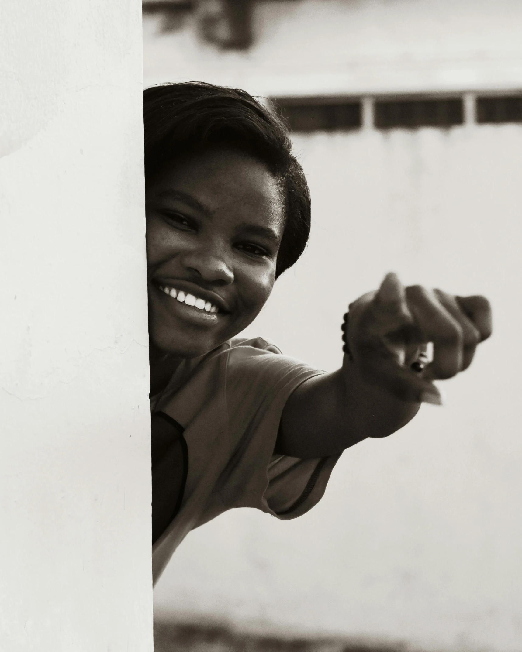 black and white pograph of a girl peeking out a wall