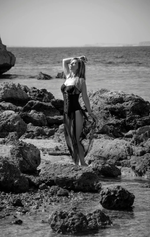 a woman standing on rocks near the ocean