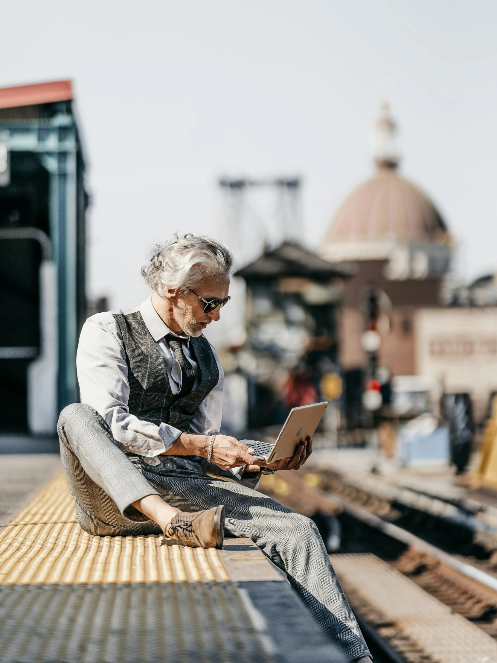 an elderly person sitting on a bench with a laptop