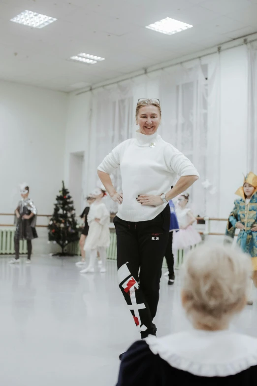 a woman standing in a ballerina costume talking to a child