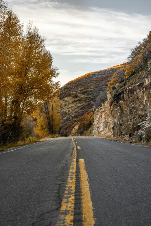 a view of the side of an empty road, with a mountain behind it