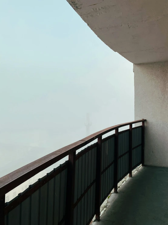 the balcony is overlooking the water on a foggy day