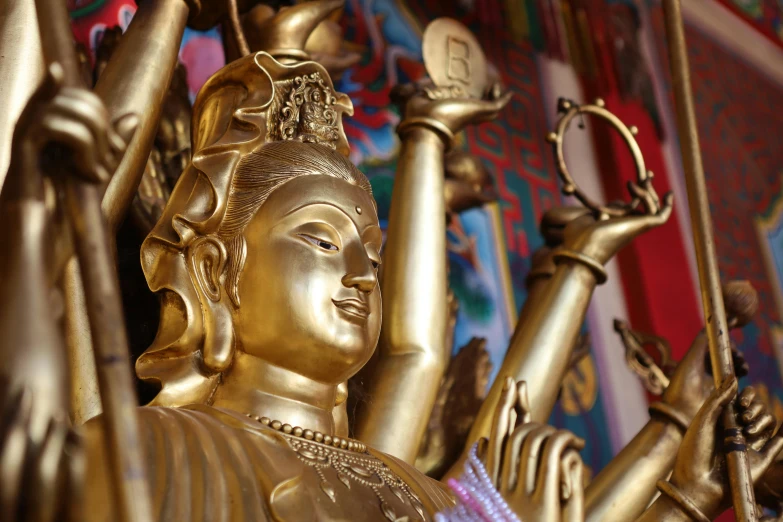 a golden buddha statue sitting outside with his arms outstretched