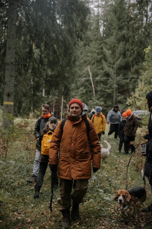 several people in brown and orange jackets walk through the woods