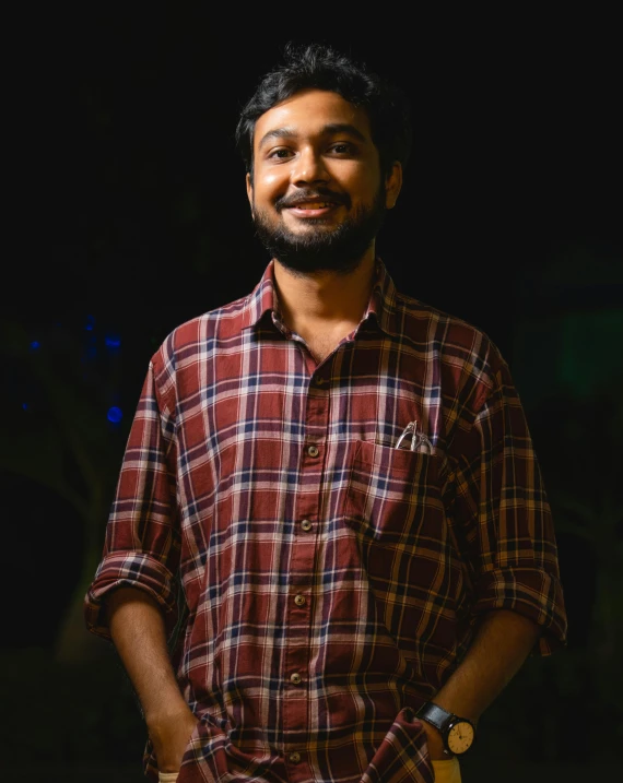 a man wearing a plaid shirt in the dark