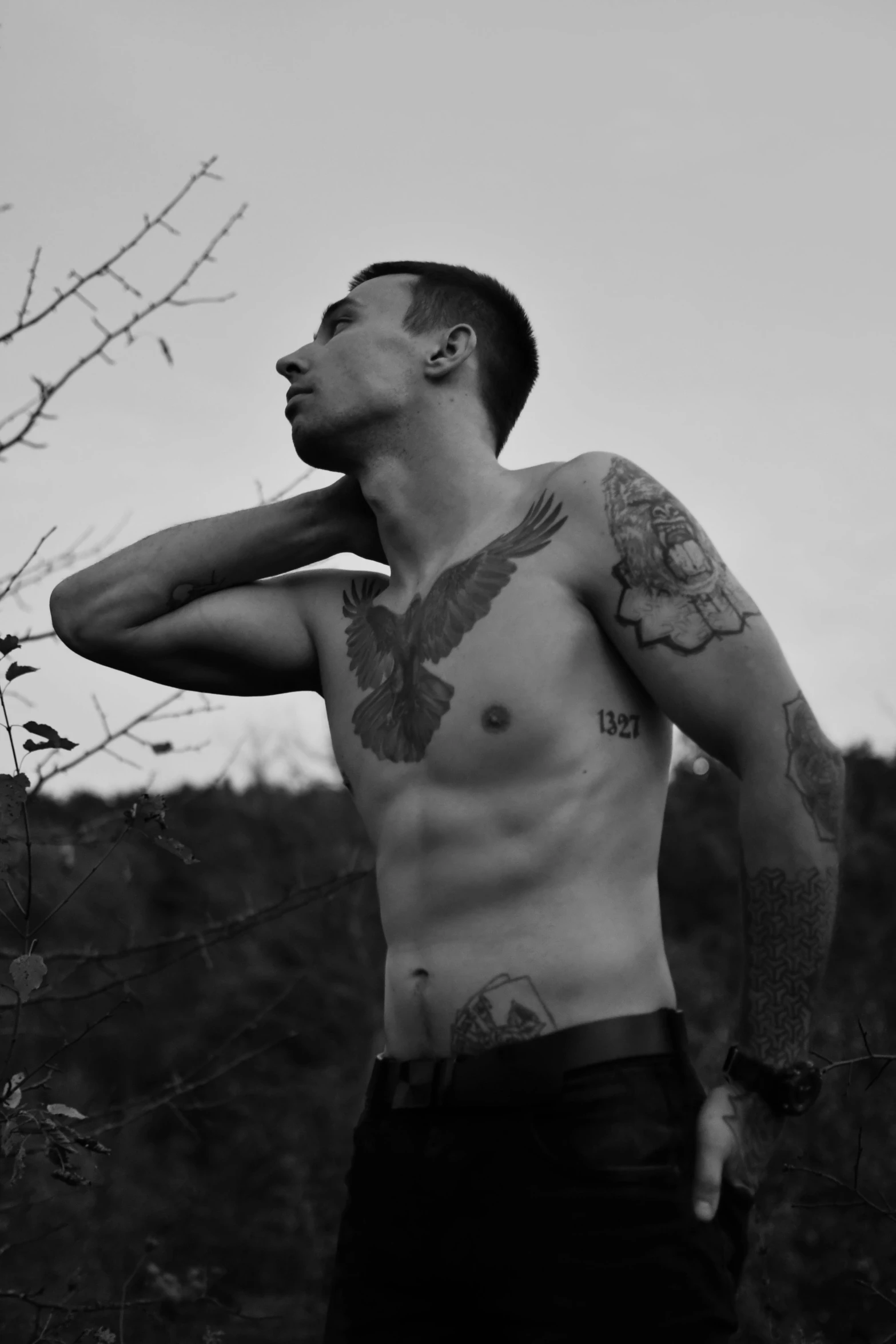 a man with tattoos is outside while holding his arm near his chest