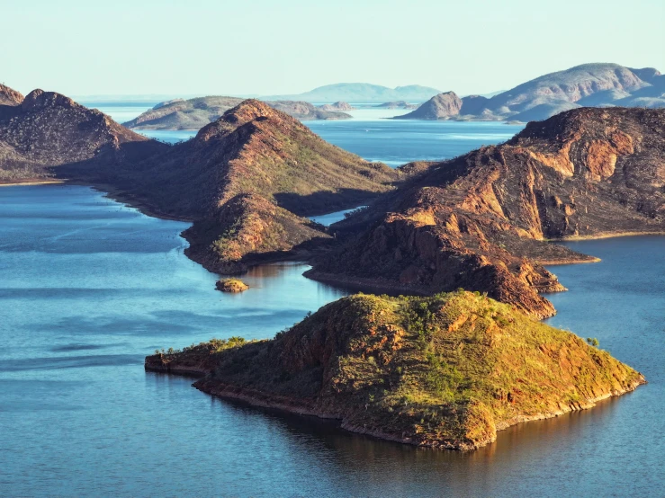 an island sitting on top of a large lake next to mountains