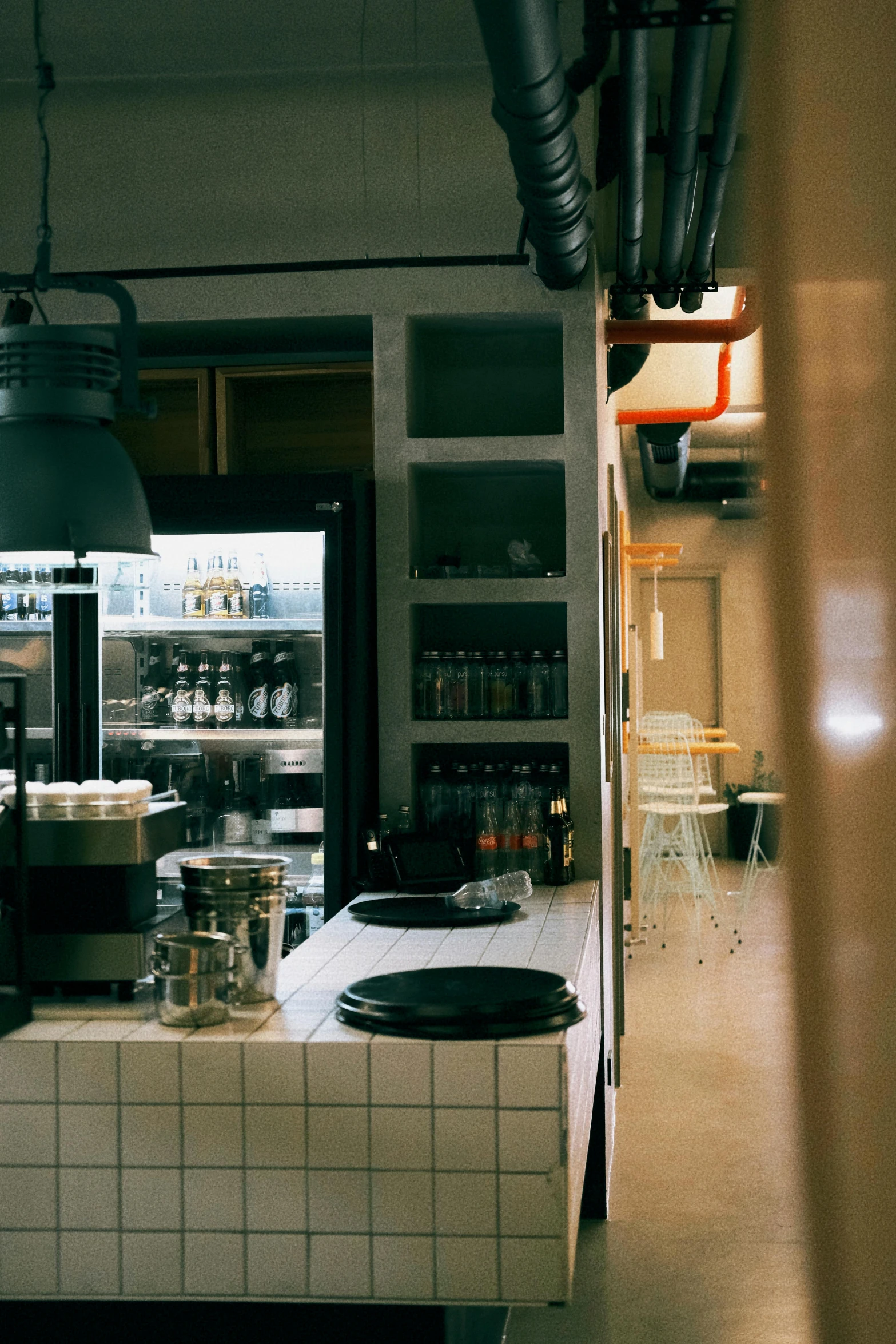 a kitchen area with a table, lights, pot holders, and appliances