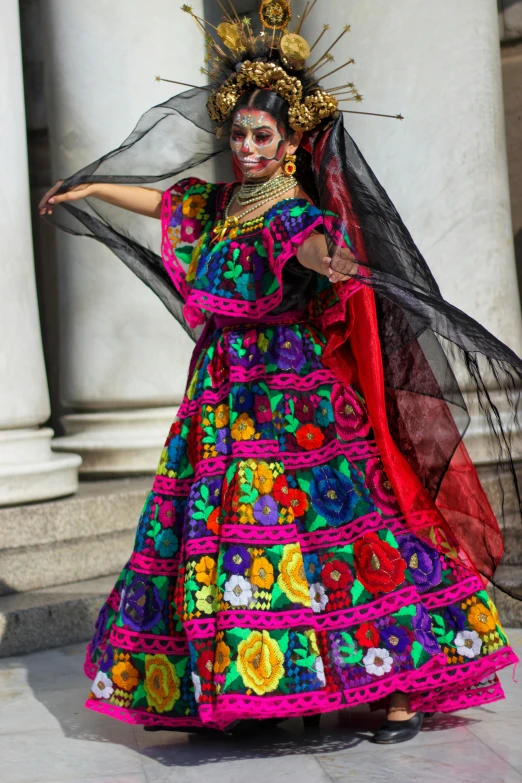 a woman in brightly colored mexican costumes posing in front of a building