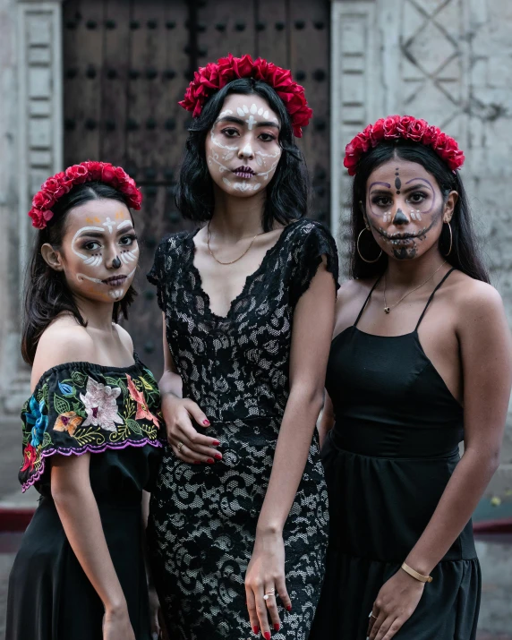 three women in face paint posing together outside