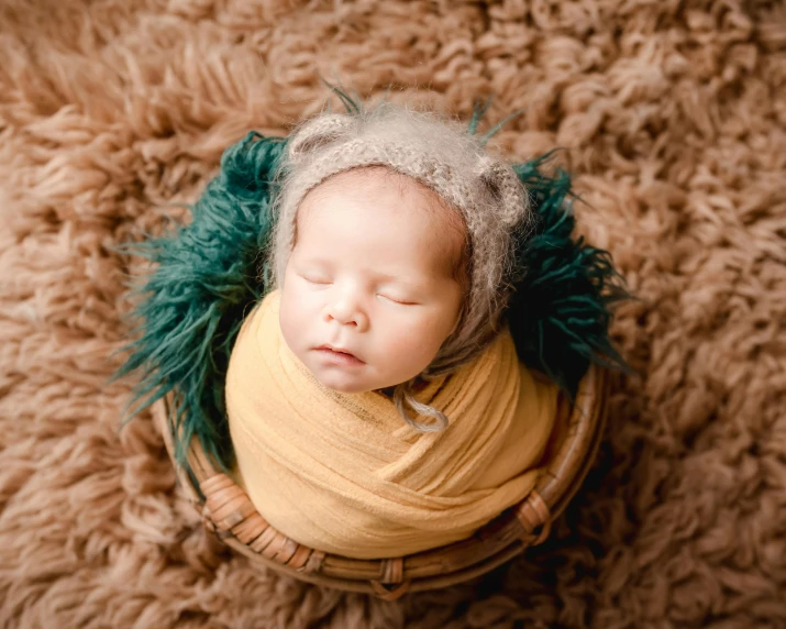 a baby curled up in a blanket is laying on a carpet