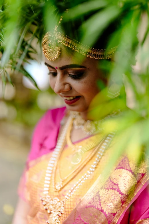 an indian woman wearing a colorful dress standing next to green plants