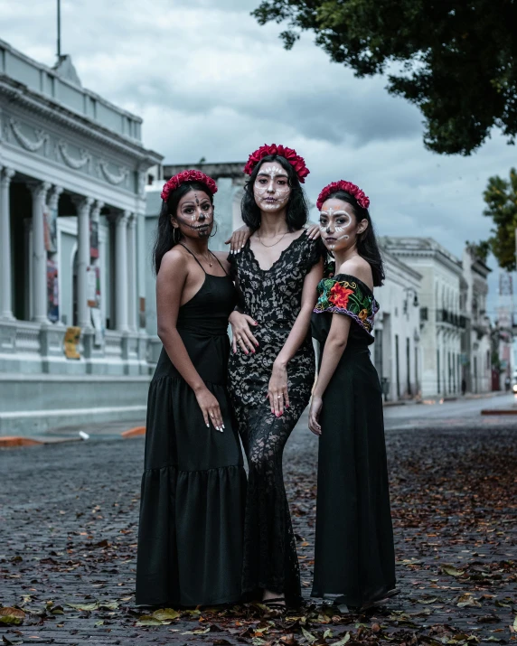 three women wearing black dresses with pink flower wreaths on their heads