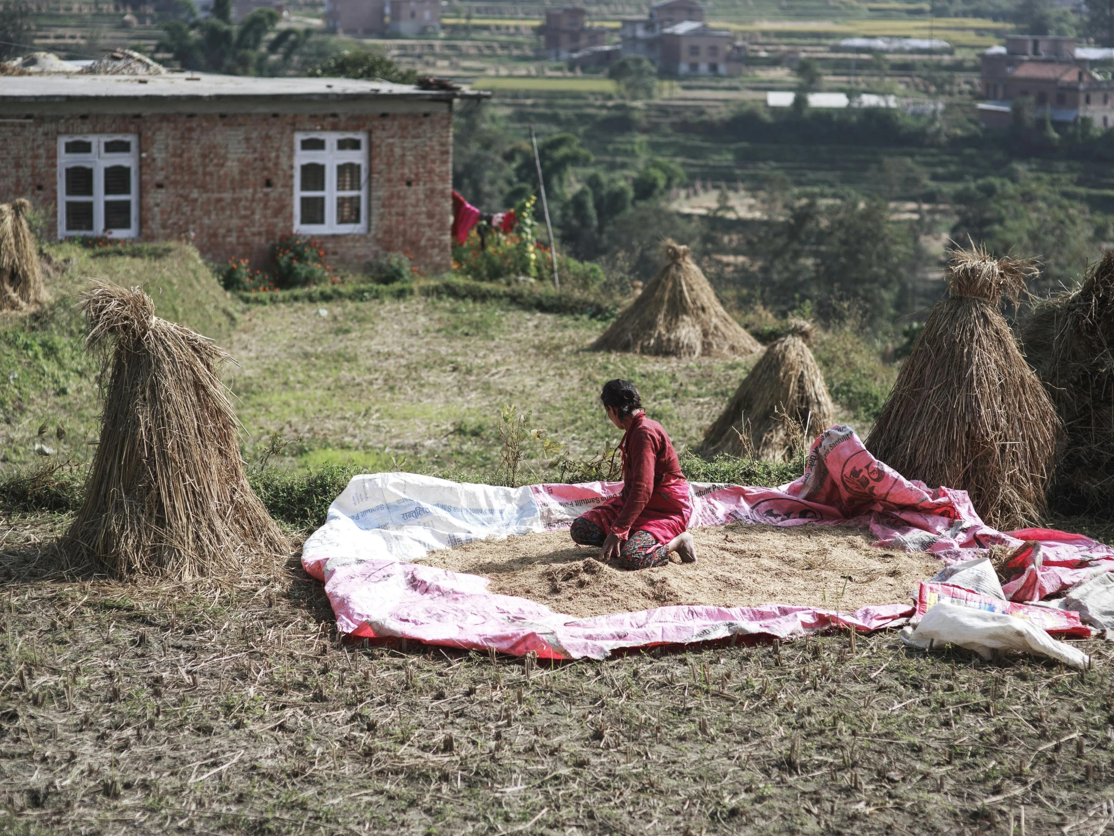 the man is sitting in front of a huge pile of hay