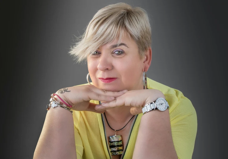 a woman with blonde hair wearing celets and a yellow shirt